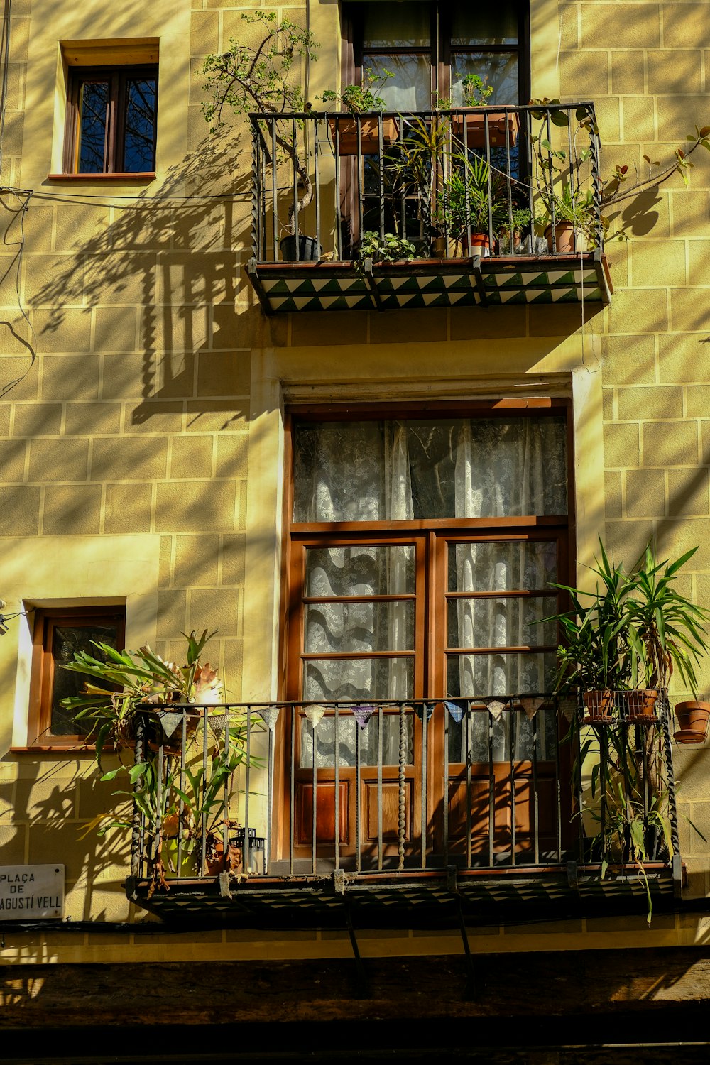 a yellow building with a balcony with plants on it