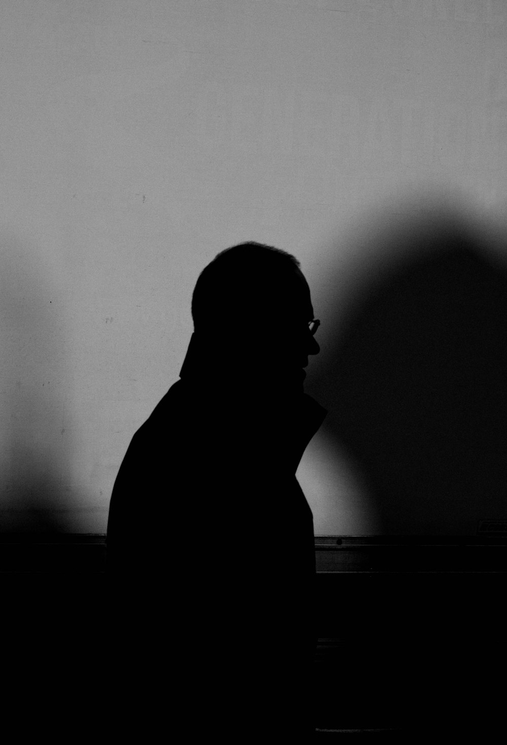 a man standing in front of a wall with a shadow on it