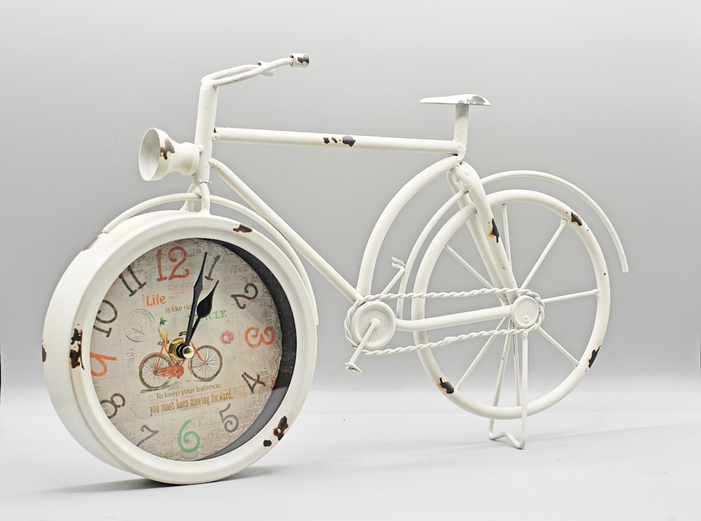 a white bicycle with a clock inside of it