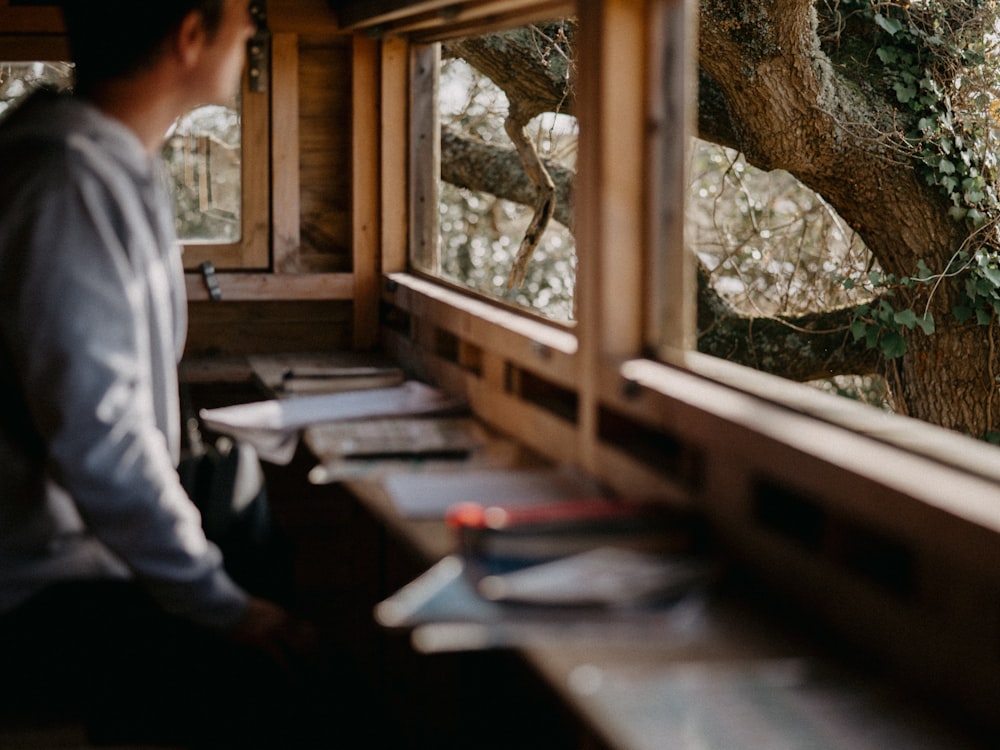 a man looking out a window at a tree