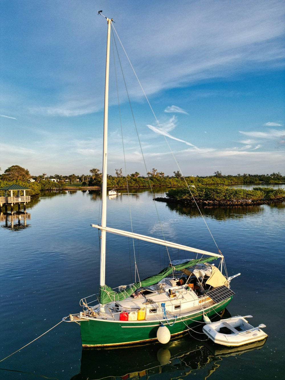 a green sailboat floating on top of a body of water