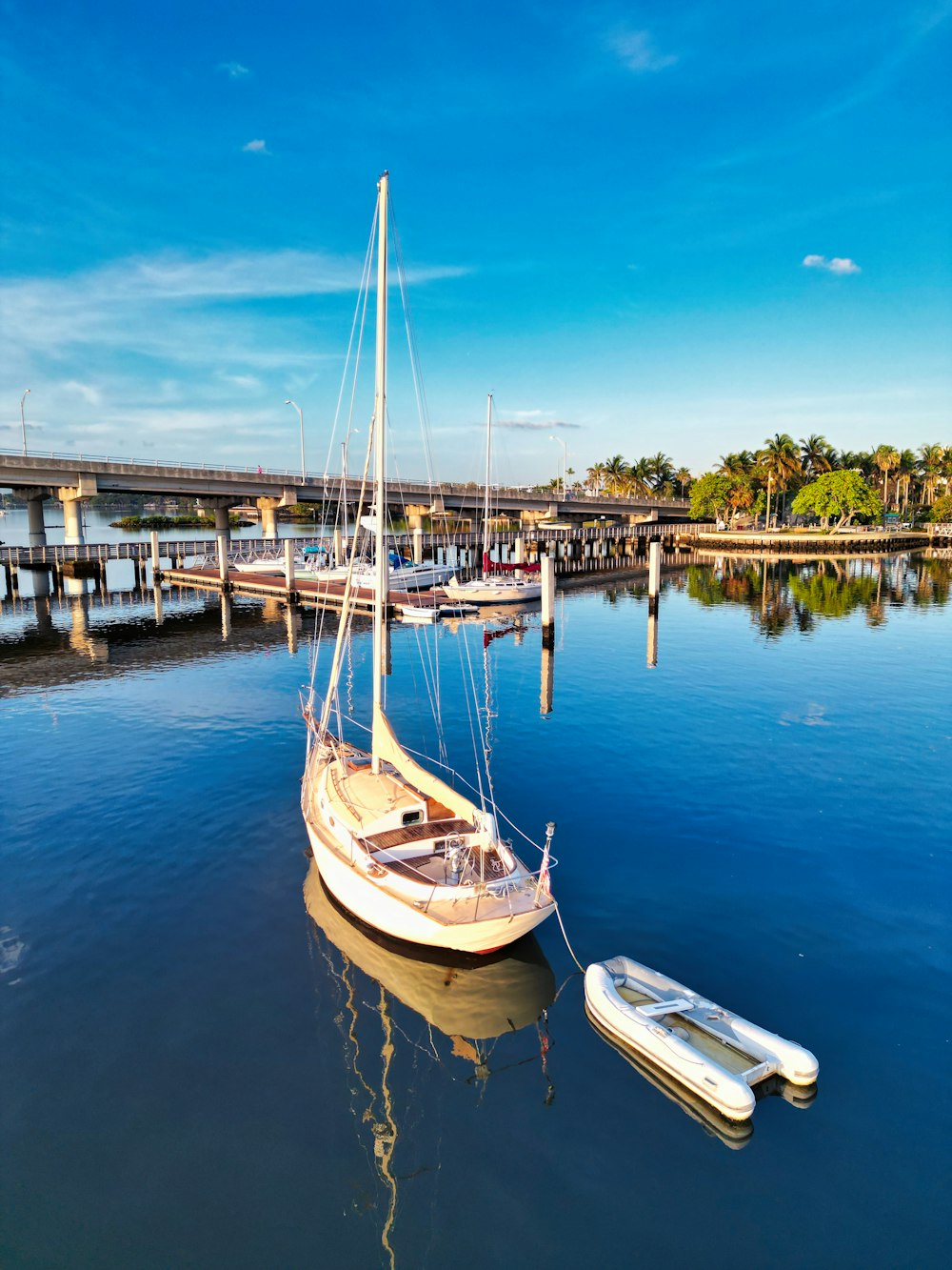 a small sailboat in the water near a bridge