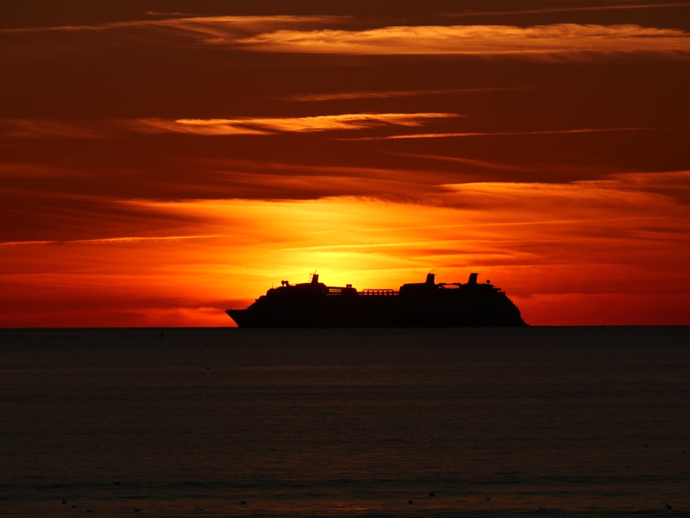 a cruise ship is silhouetted against an orange sunset