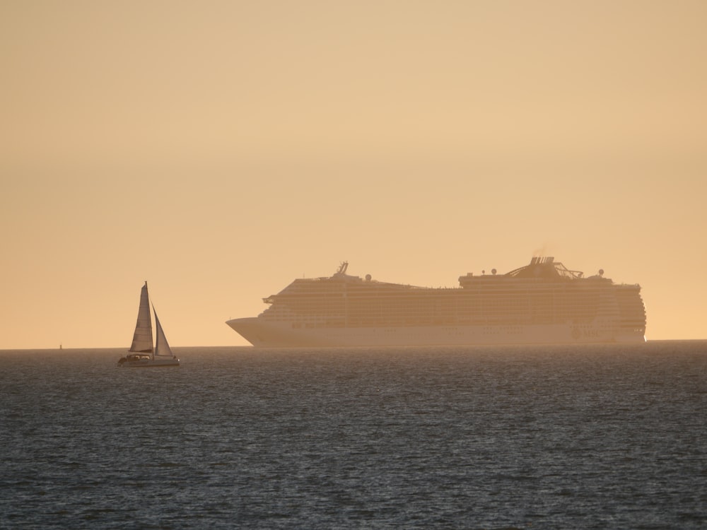 a large cruise ship in the distance with a sailboat in the foreground
