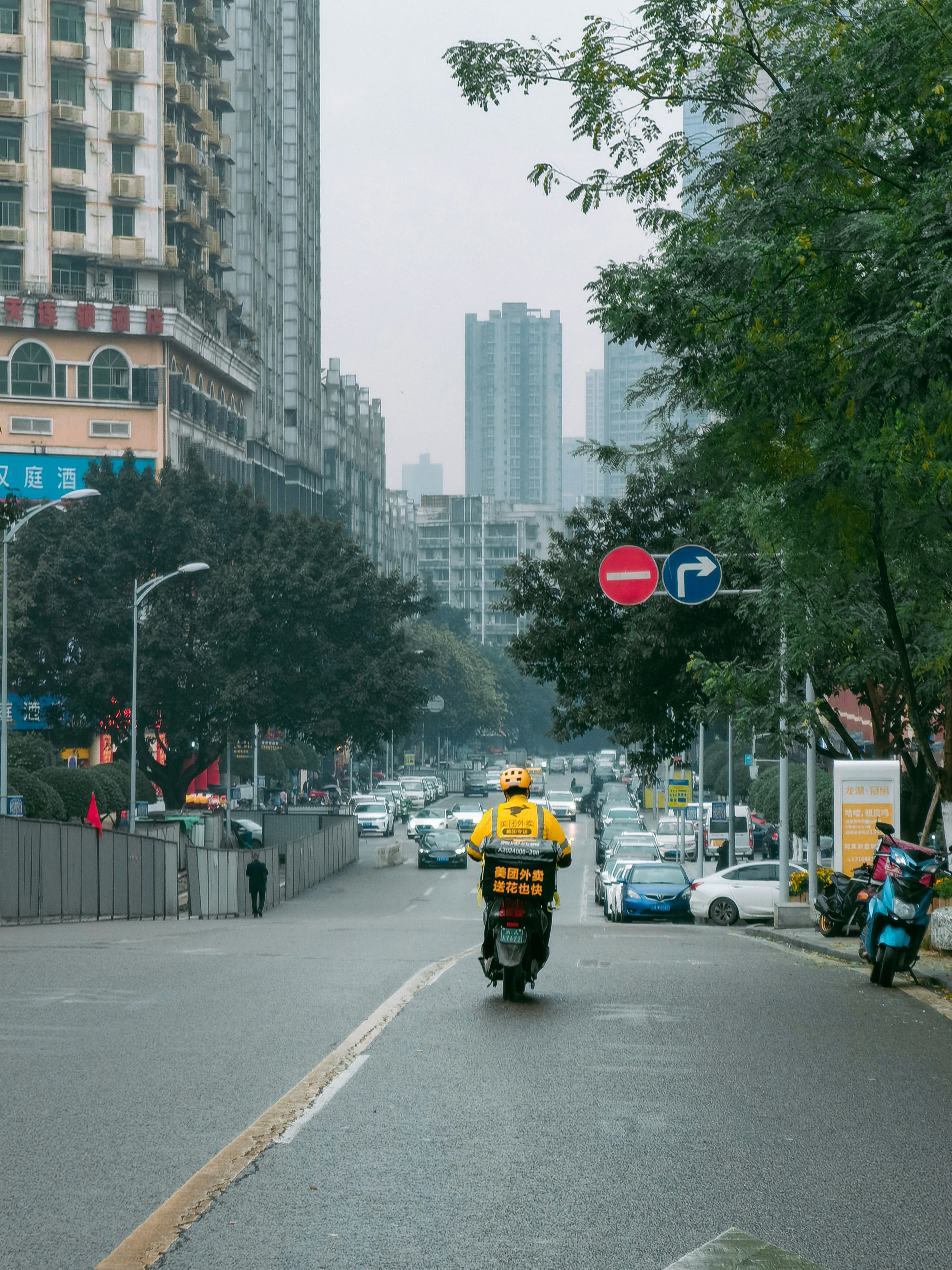 a man riding a motorcycle down a street next to tall buildings