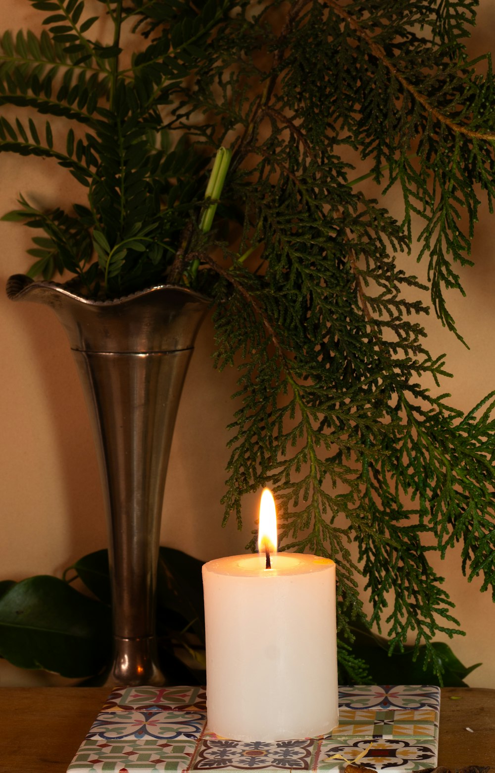 a lit candle sitting on a table next to a vase