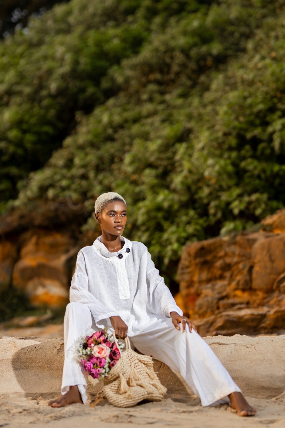 a woman sitting on a beach with a basket of flowers