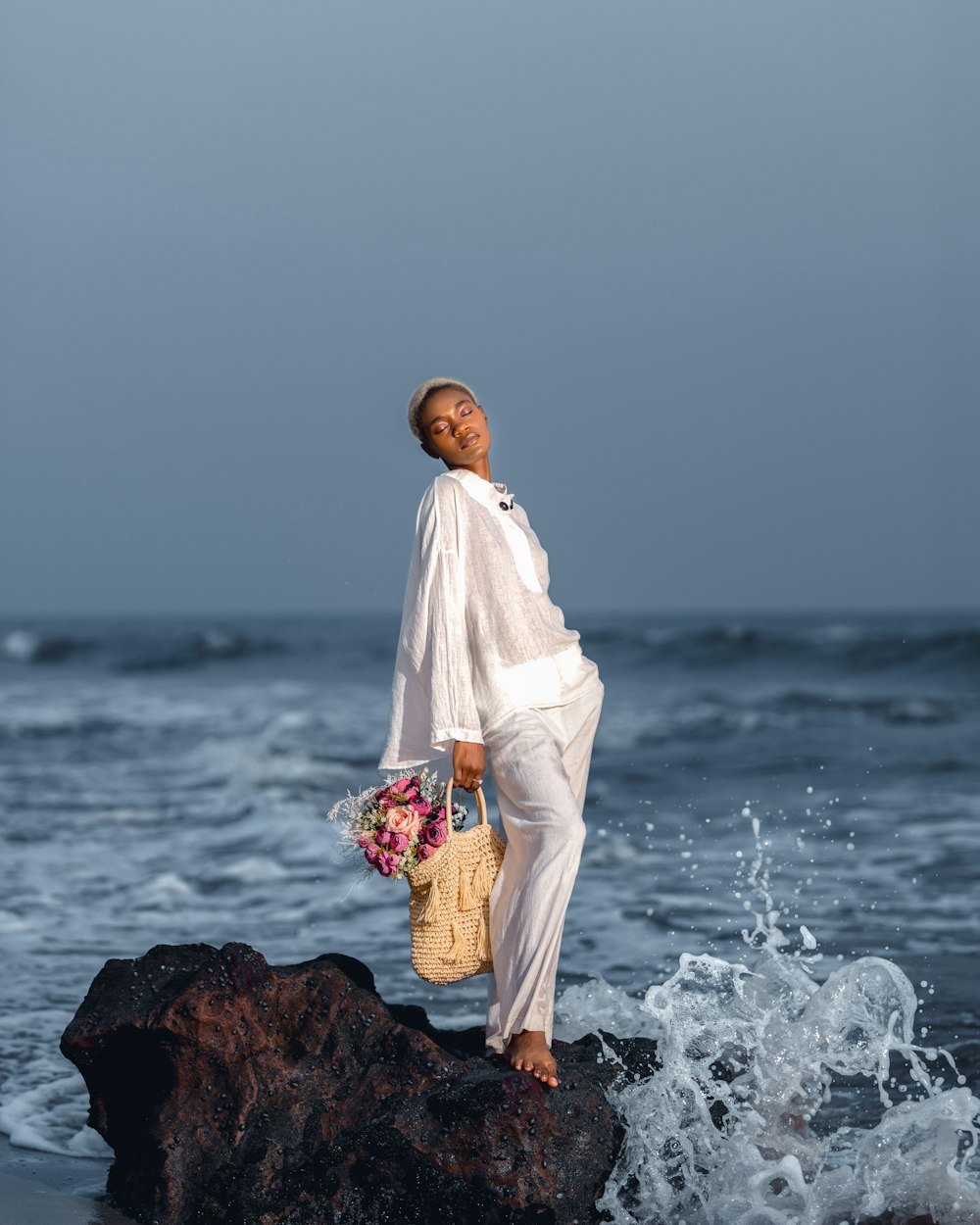 a woman standing on top of a rock near the ocean