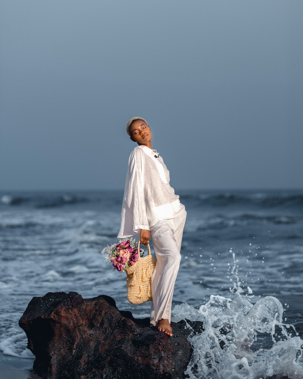 海辺の岩の上に立つ女性