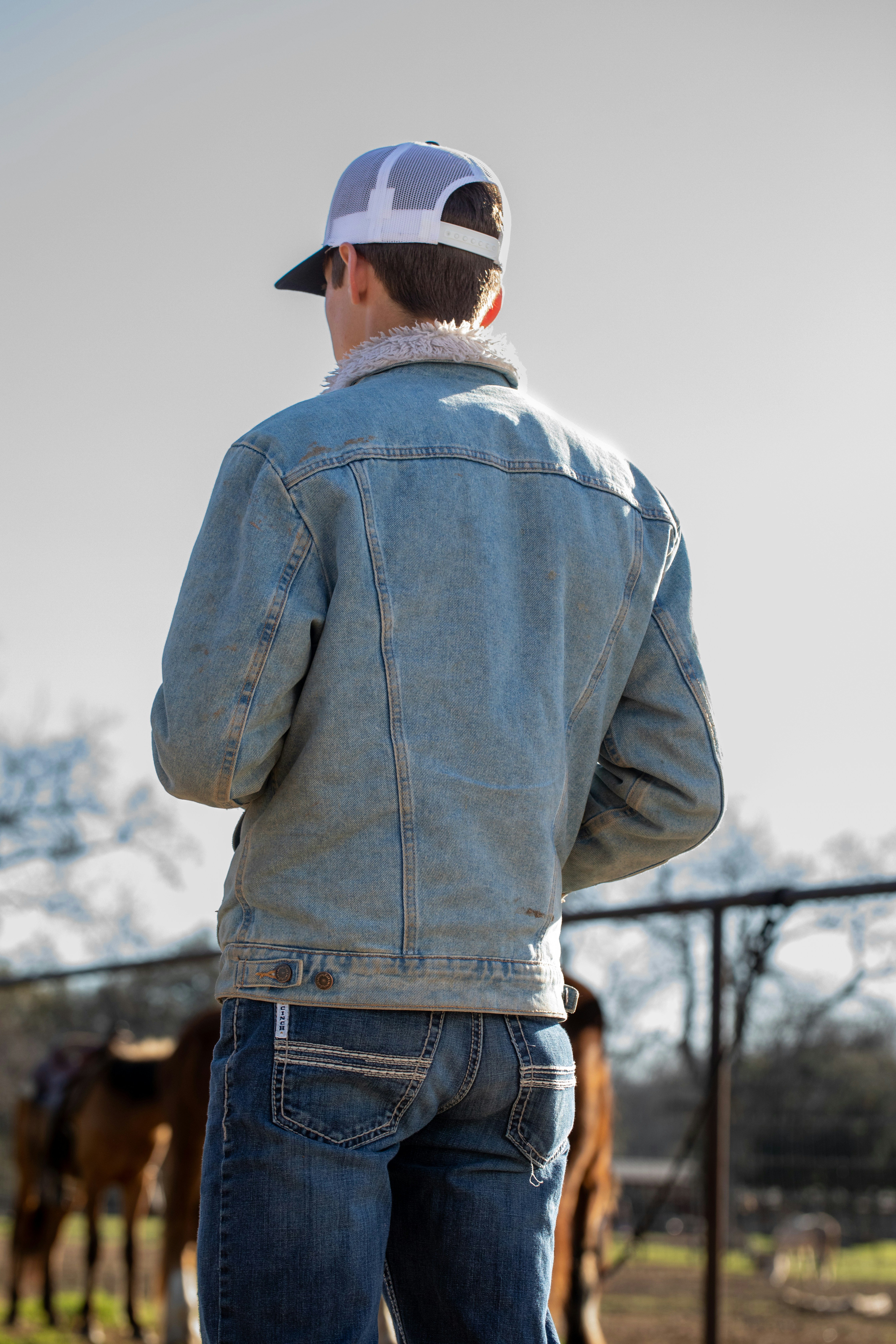 a man standing in front of a fence looking at cows
