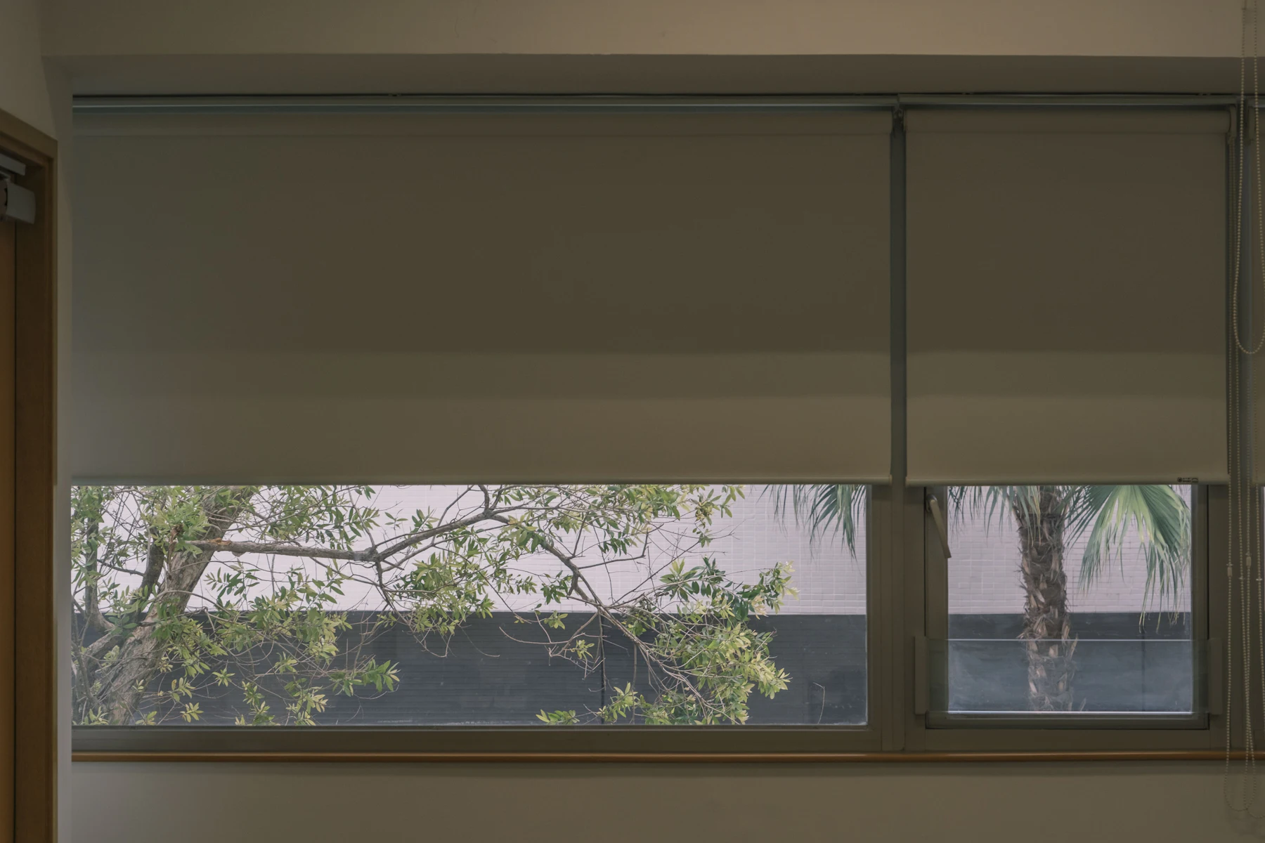Toile solaire sur mesure filtrant le soleil devant une grande fenêtre tout en gardant la vue