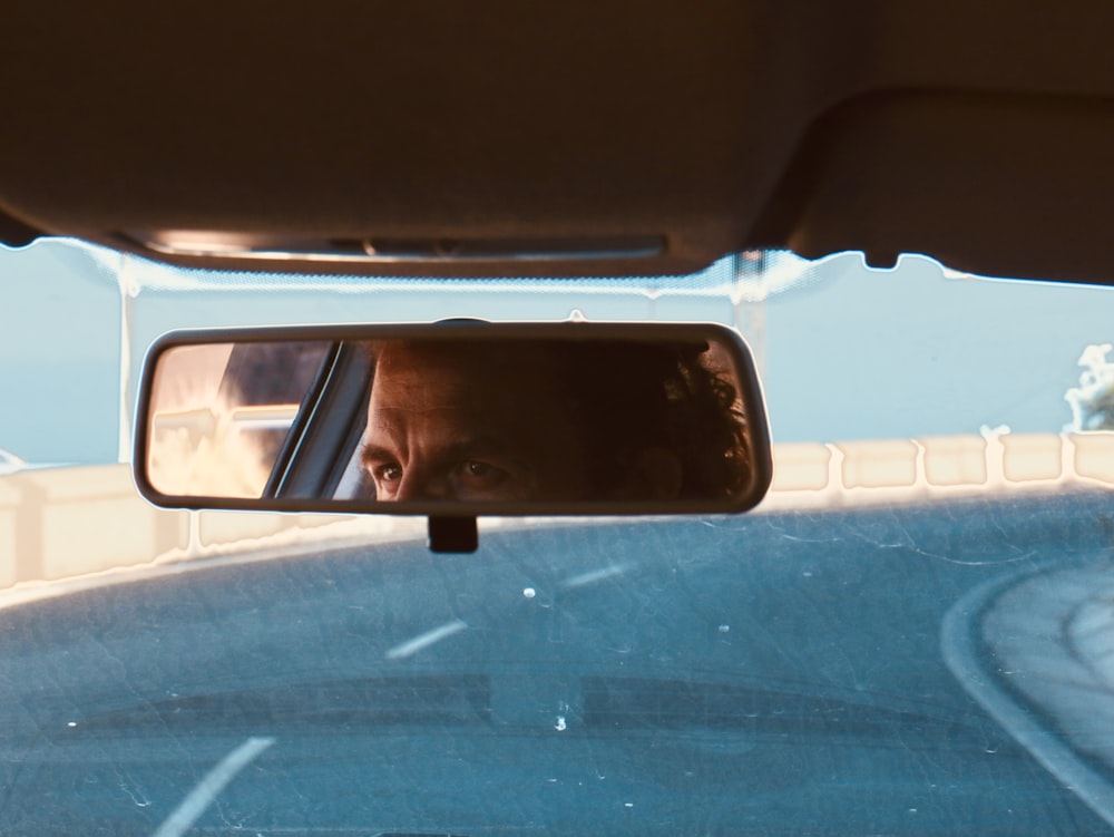 a man is seen in the rear view mirror of a car