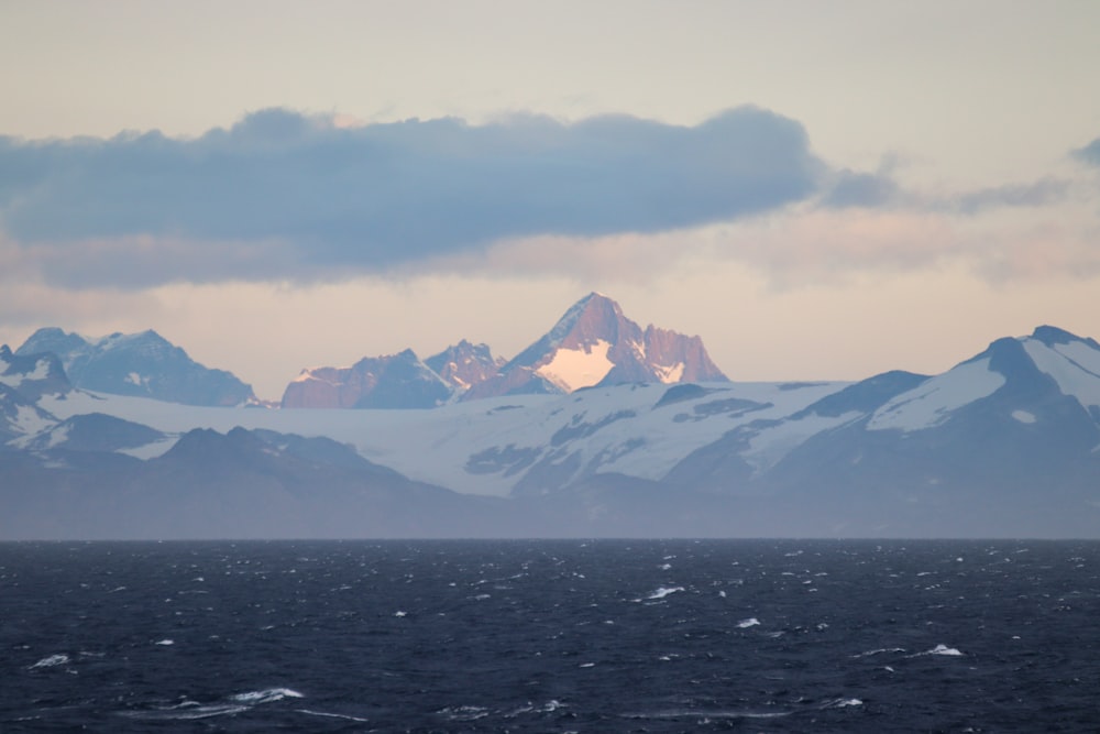 the mountains are covered in snow as the sun sets