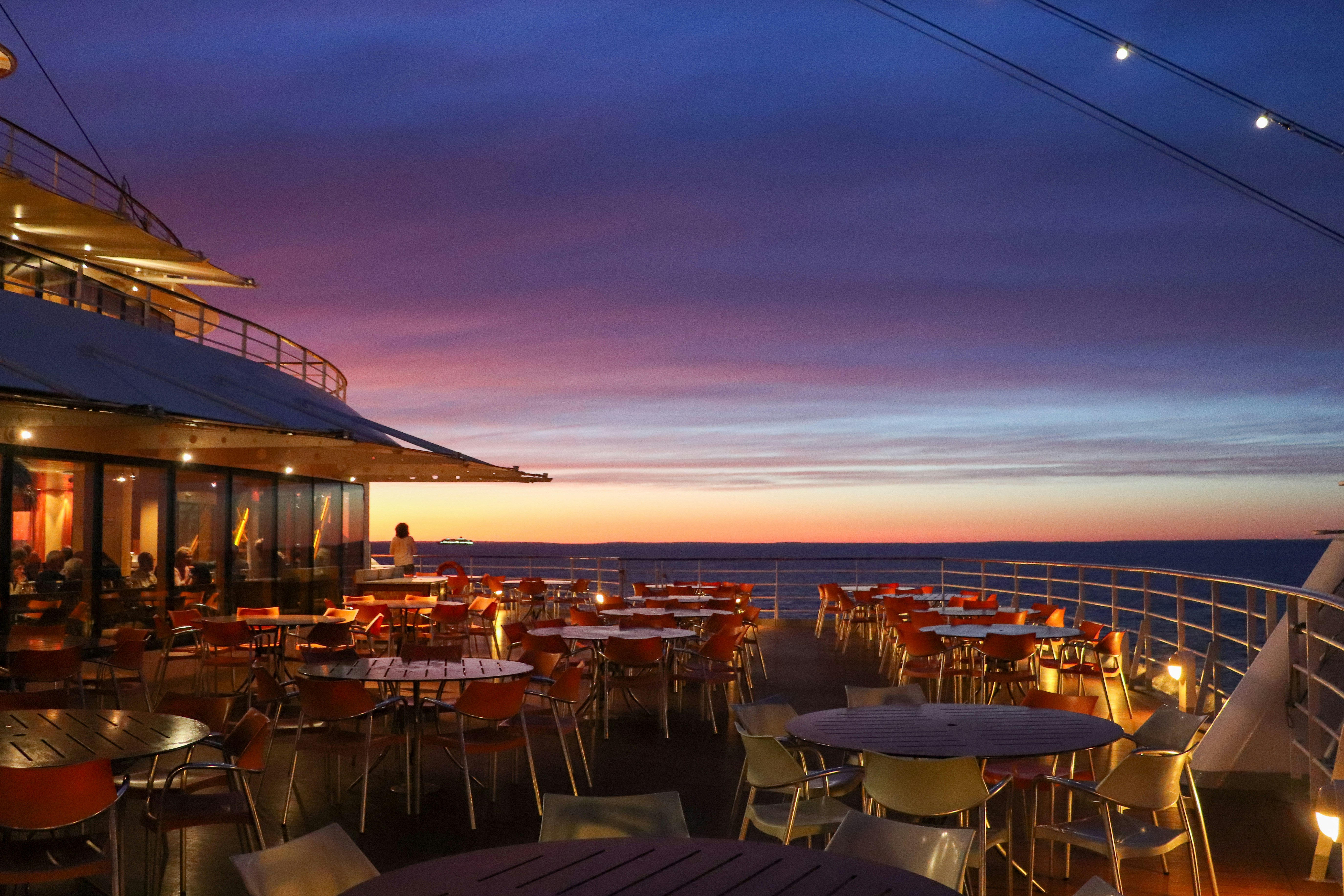 the deck of a cruise ship with tables and chairs
