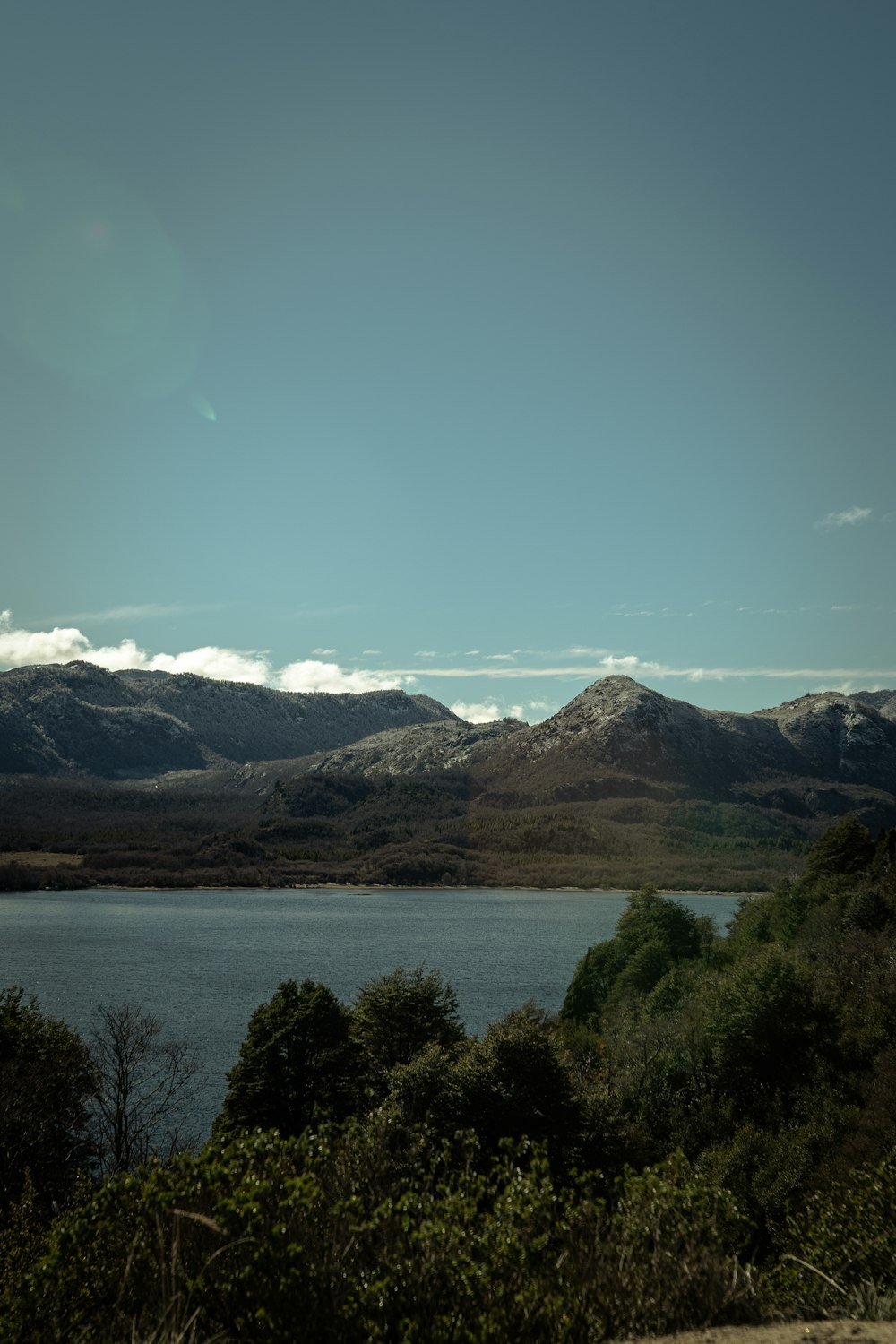 a lake surrounded by mountains under a blue sky