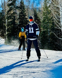 a couple of people riding skis down a snow covered slope
