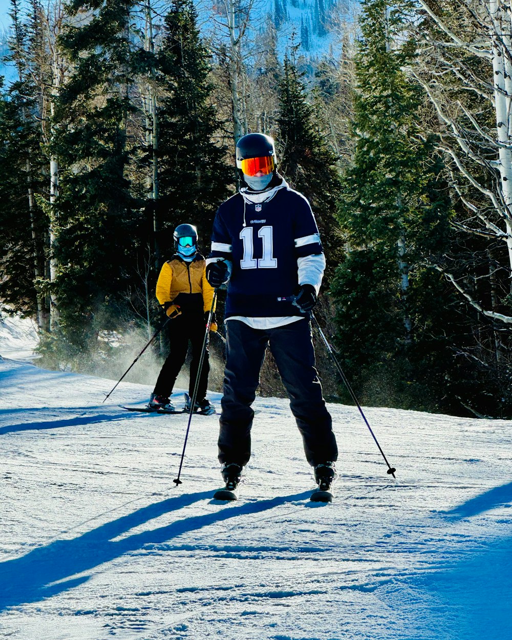 a couple of people riding skis down a snow covered slope