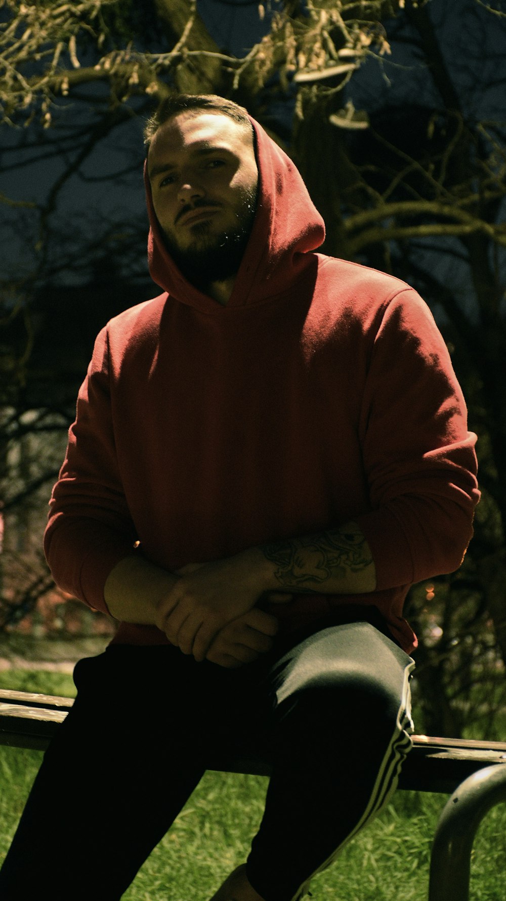 a man in a red hoodie sitting on a bench
