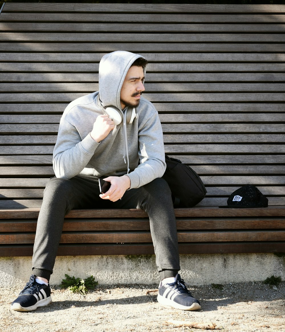 a man sitting on a bench wearing a hoodie