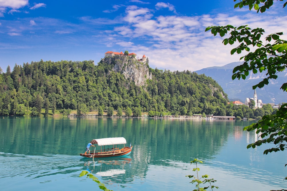 a boat floating on top of a lake next to a lush green hillside