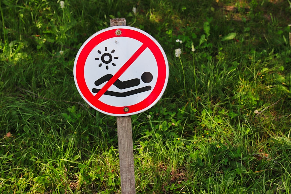 a red and white sign sitting on top of a lush green field