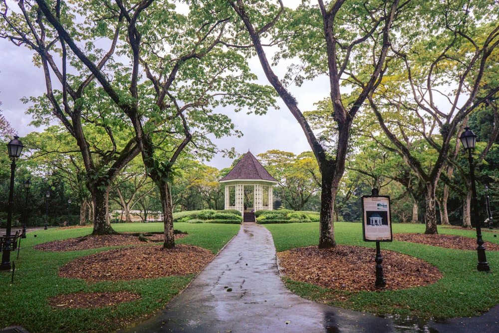 a white gazebo surrounded by trees in a park