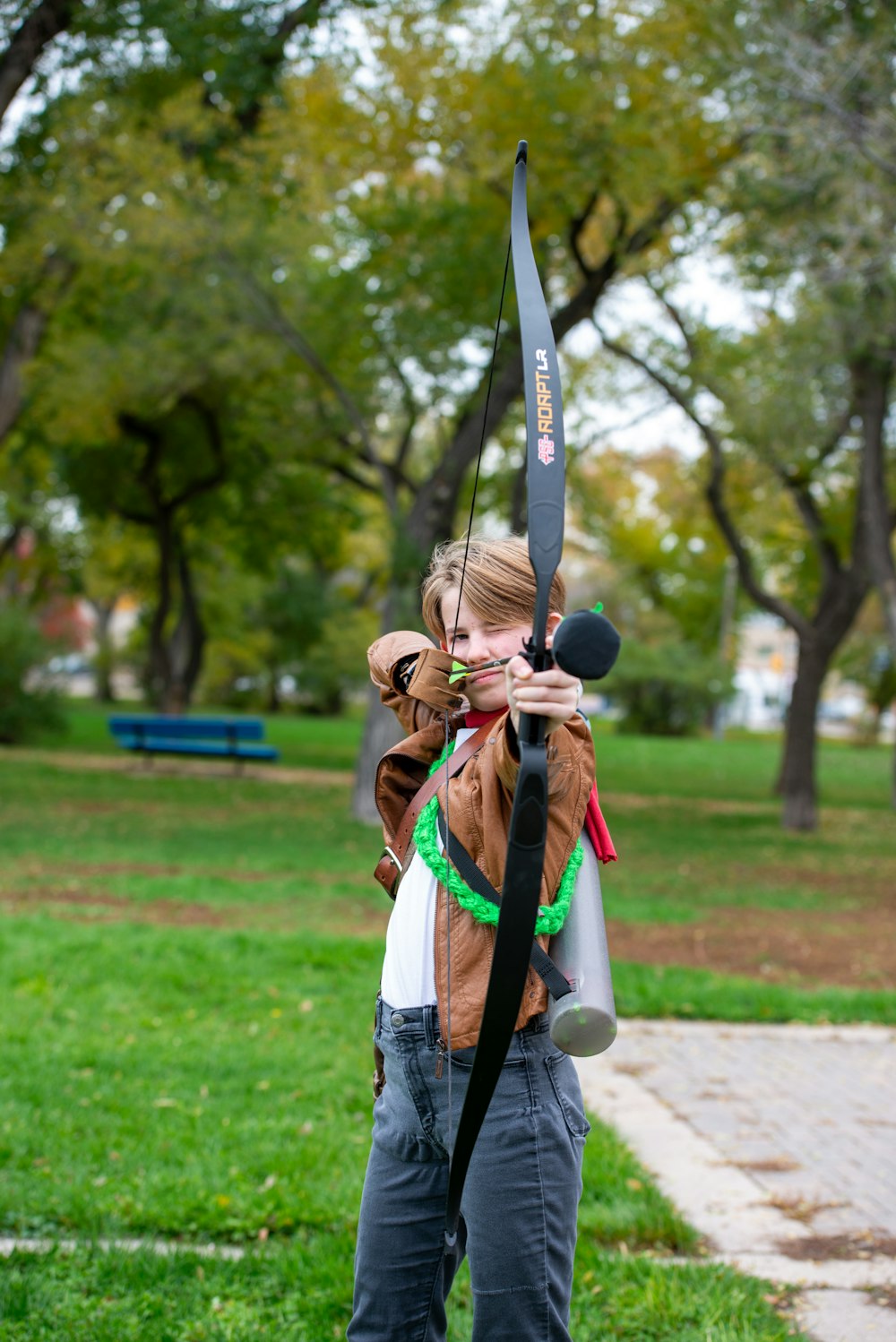 a woman holding a bow and arrow in a park