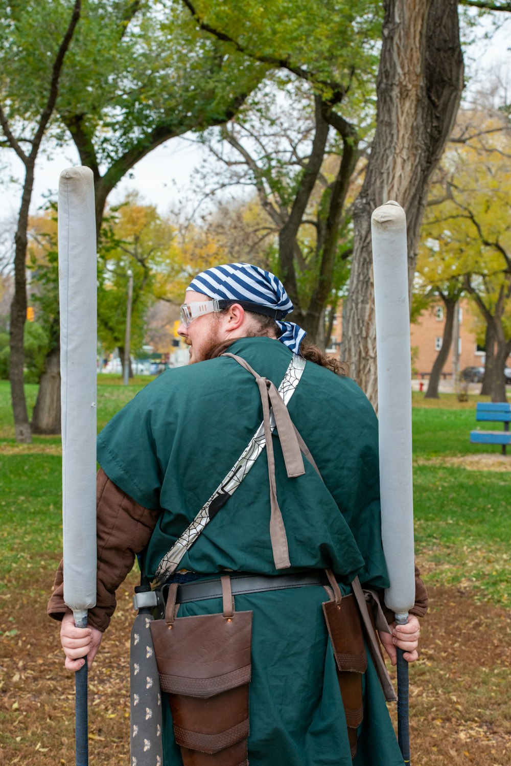 a man in a green outfit holding two poles