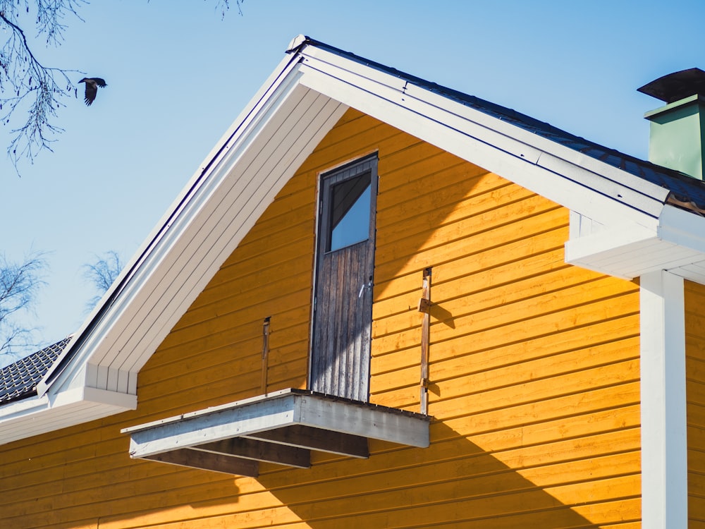 a yellow house with a black roof and a window