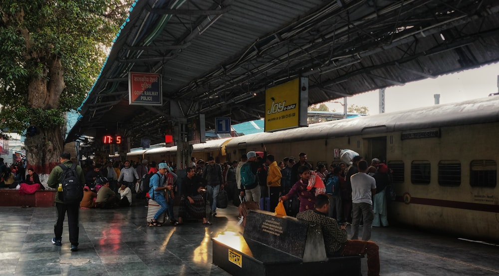 a group of people standing next to a train at a train station