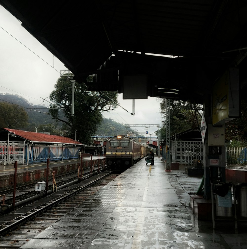 a train pulling into a train station on a rainy day