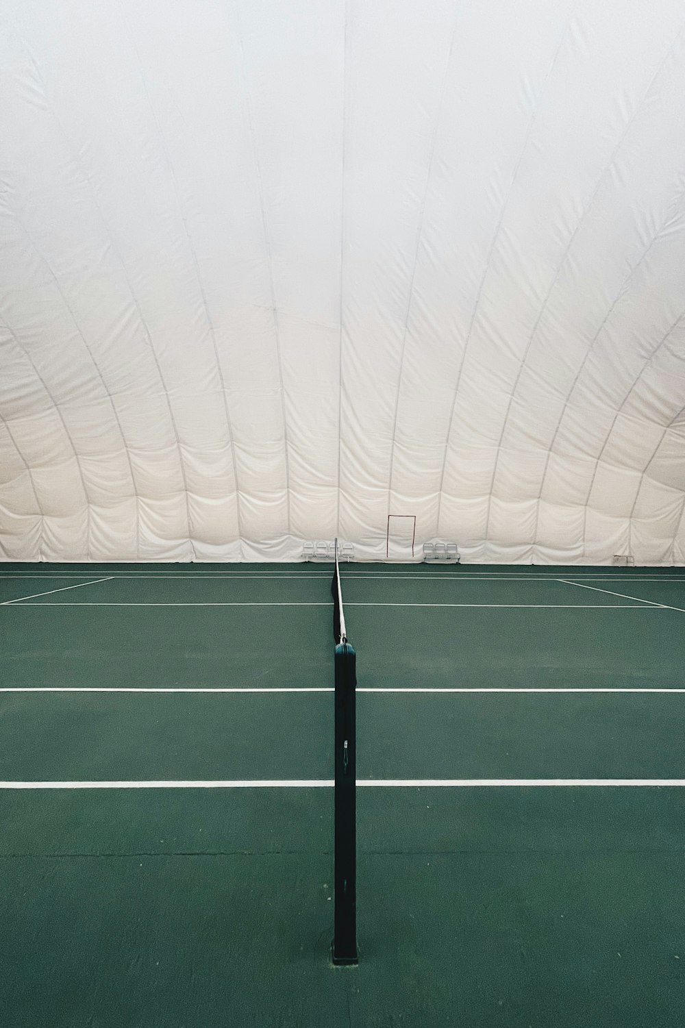 a tennis court with a white tent in the background