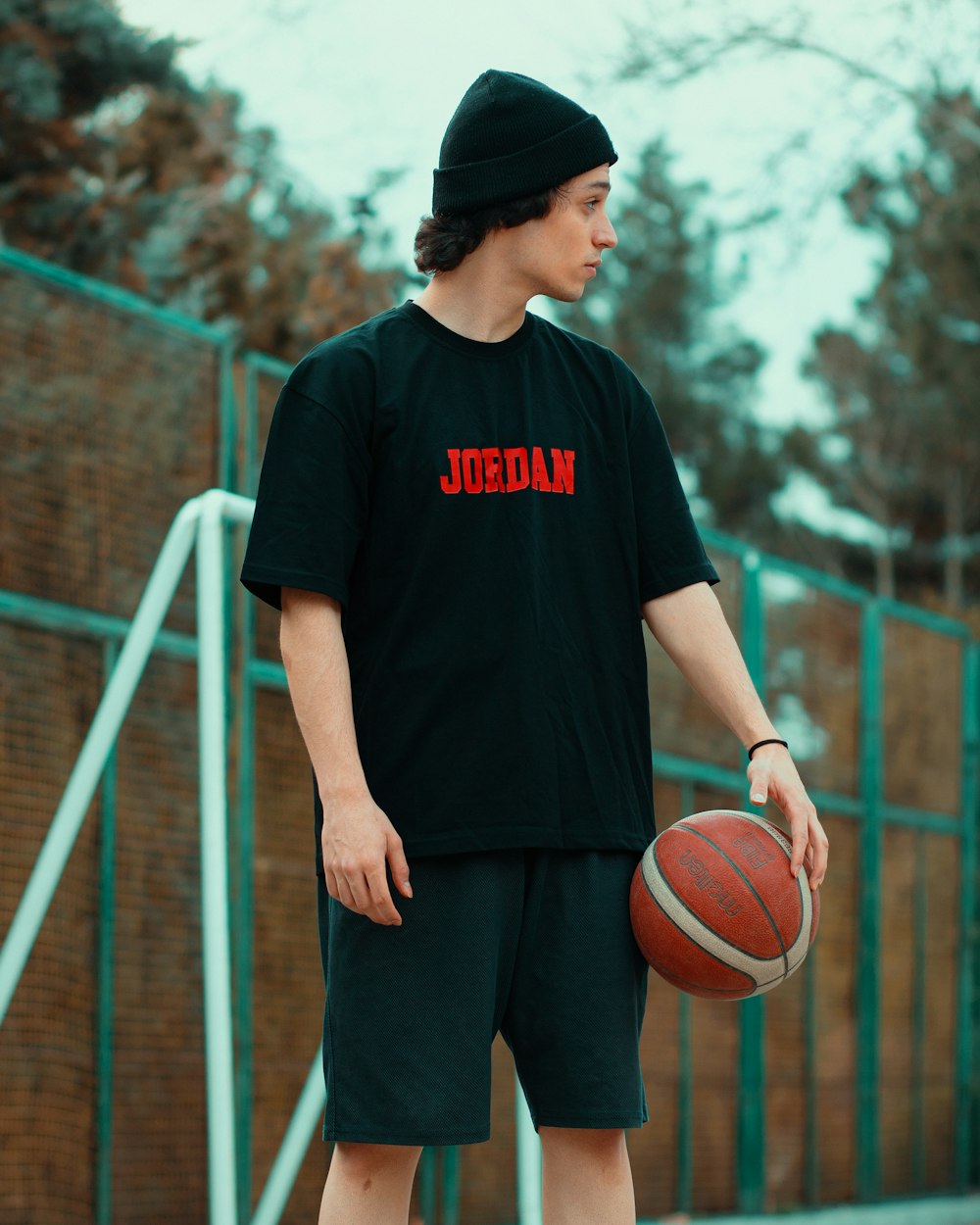 a young man holding a basketball on top of a basketball court