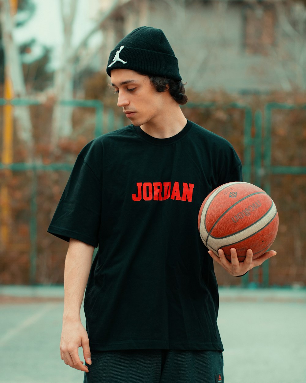 a young man holding a basketball on a basketball court