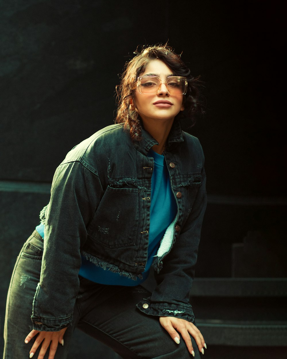 a woman wearing a jean jacket and glasses