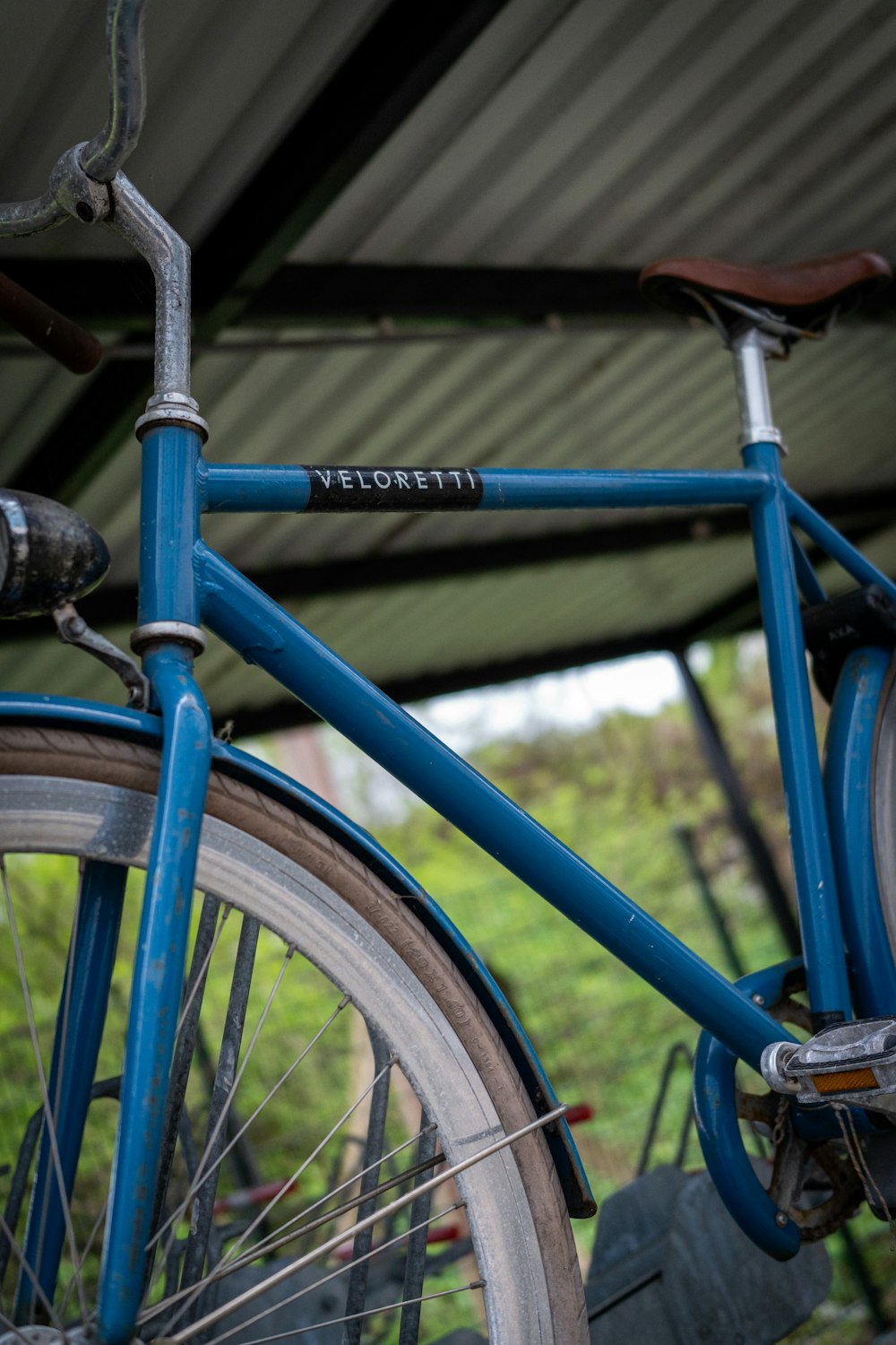 a close up of a blue bicycle parked under a roof