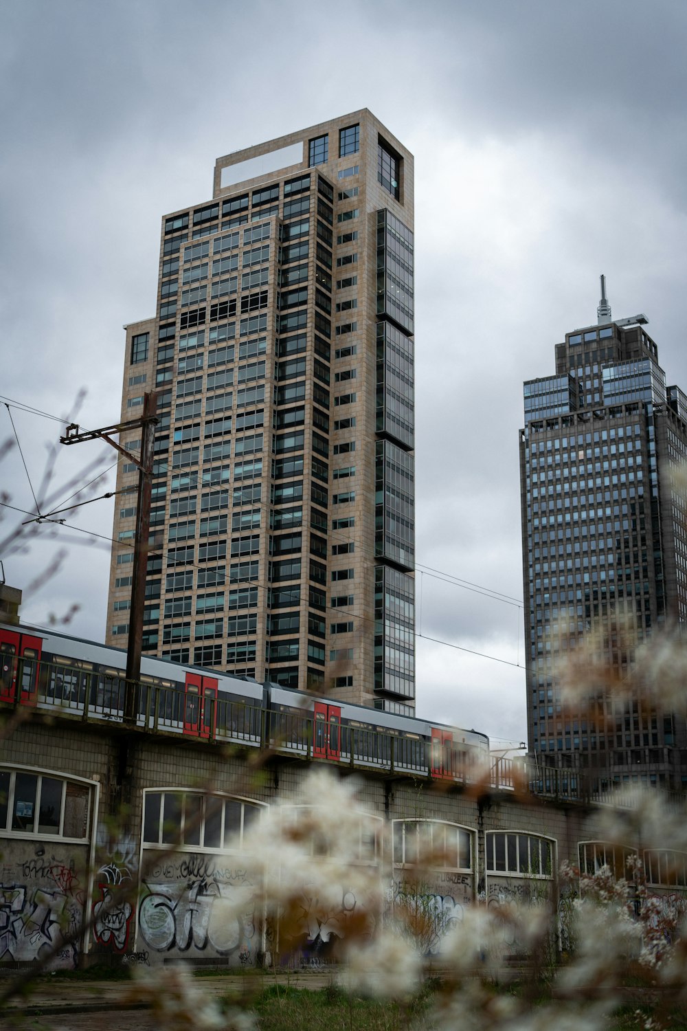 a train traveling past tall buildings on a cloudy day