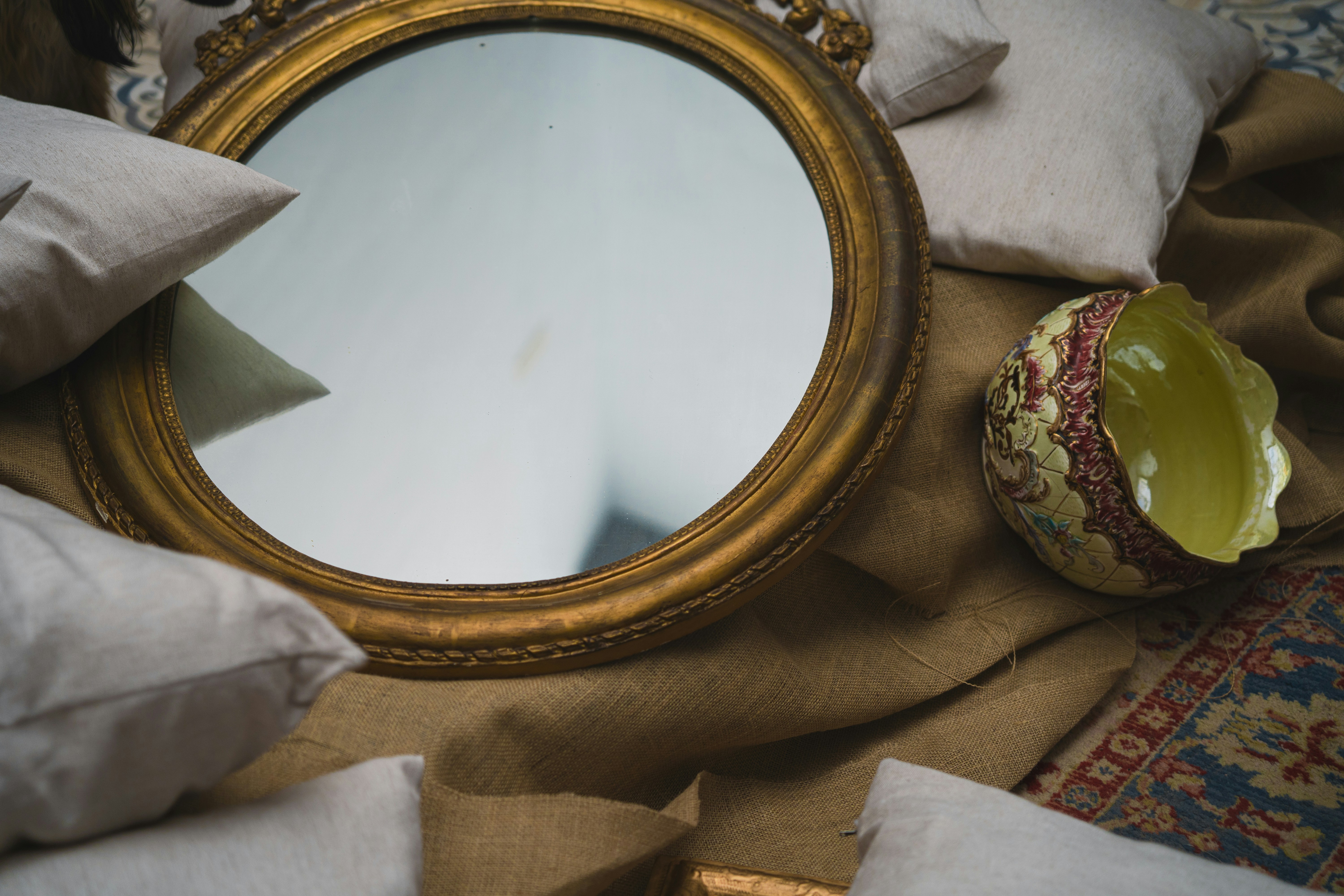 a mirror sitting on top of a bed next to pillows
