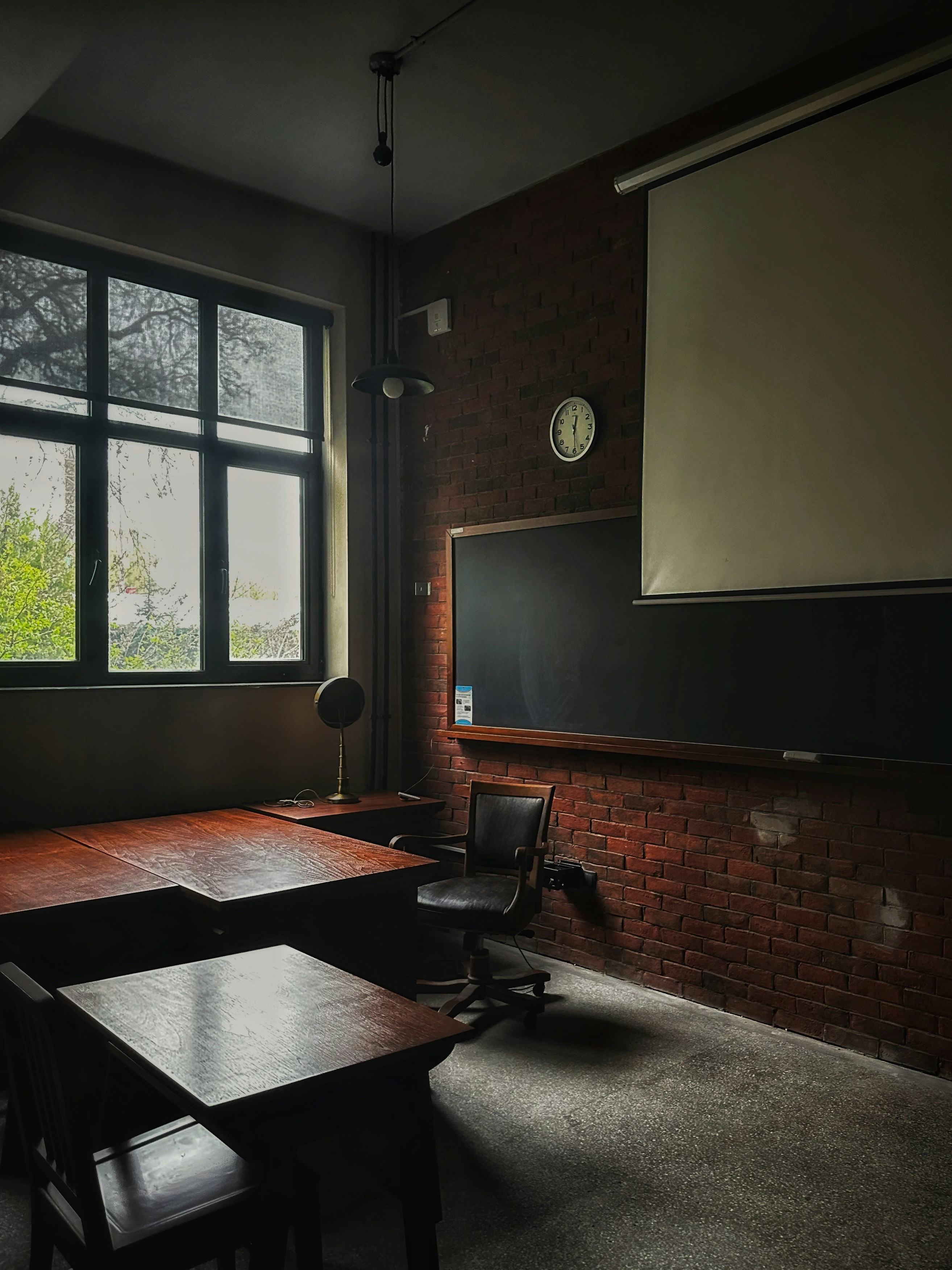Sala de clase histórica con pupitres de madera oscura y pizarrón, iluminación tenue y atmosférica