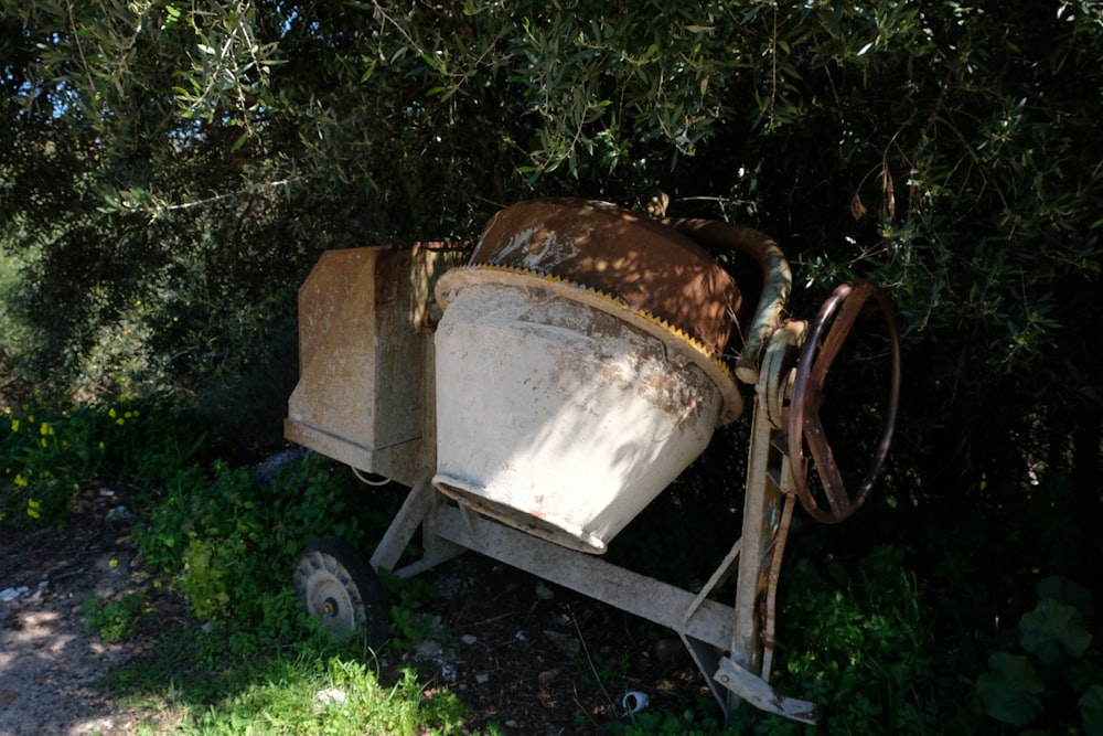 an old wheelbarrow sitting in the shade of a tree