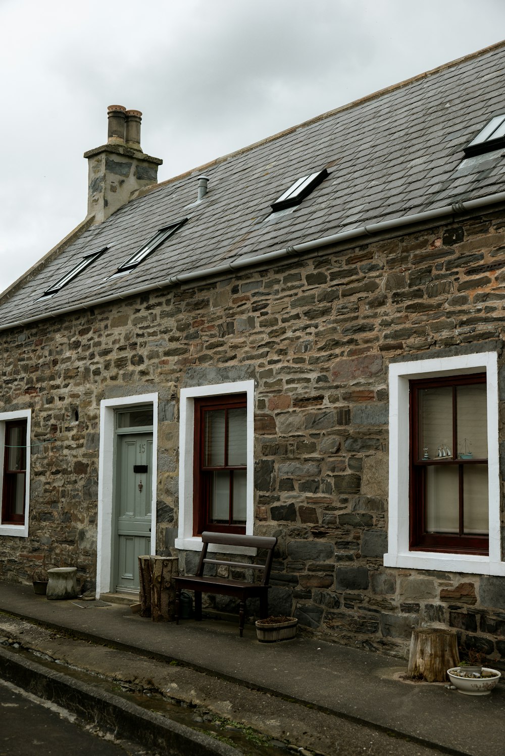 a stone building with two windows and a bench in front of it