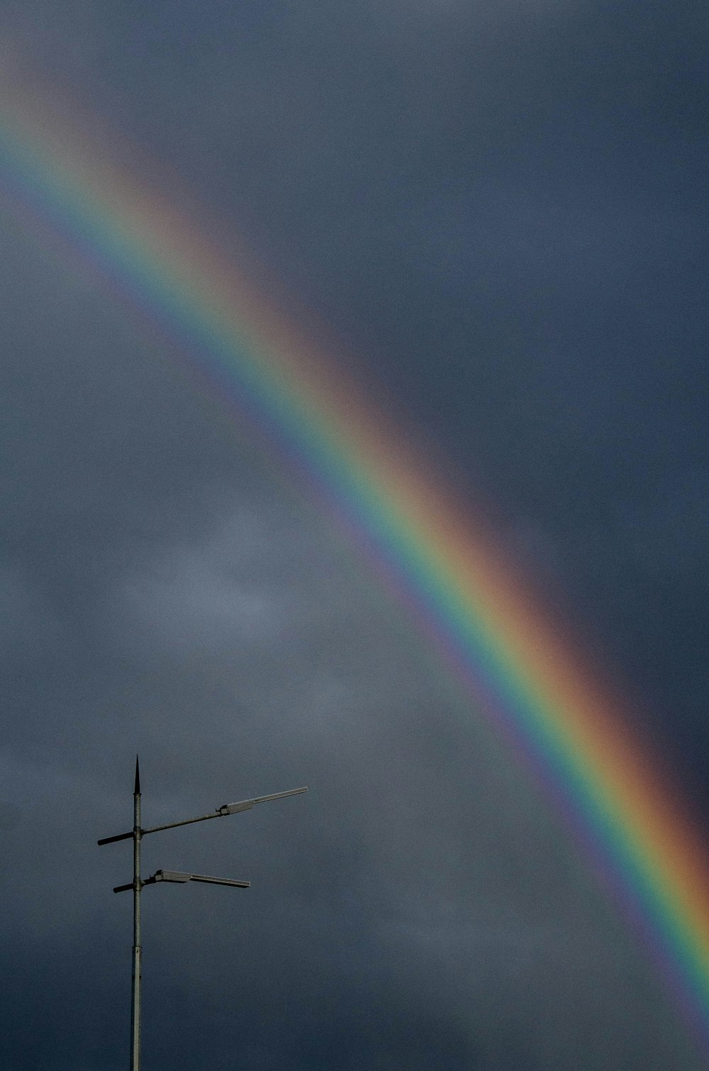 a rainbow in the sky with a weather vane in the foreground