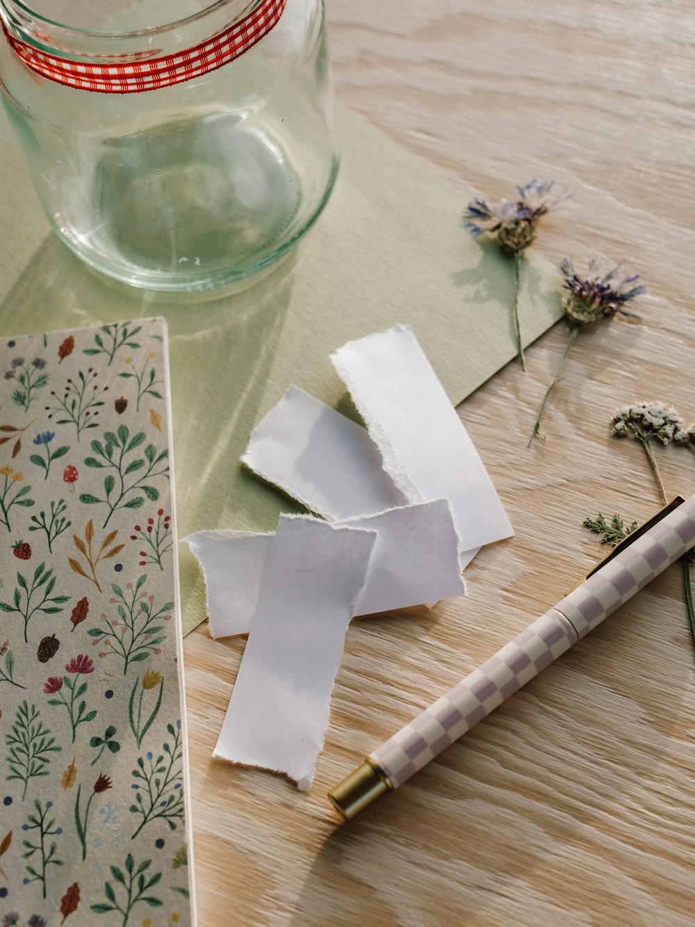 a wooden table topped with papers and a pen