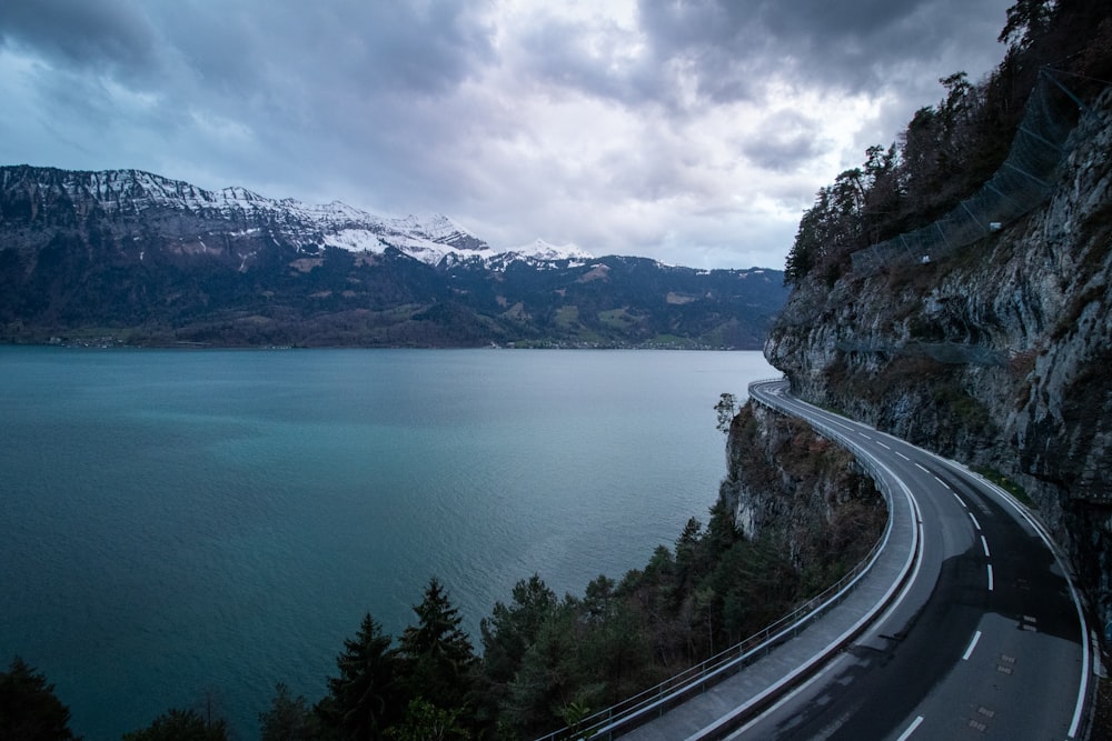 un'autostrada che scende lungo il fianco di una montagna accanto a uno specchio d'acqua