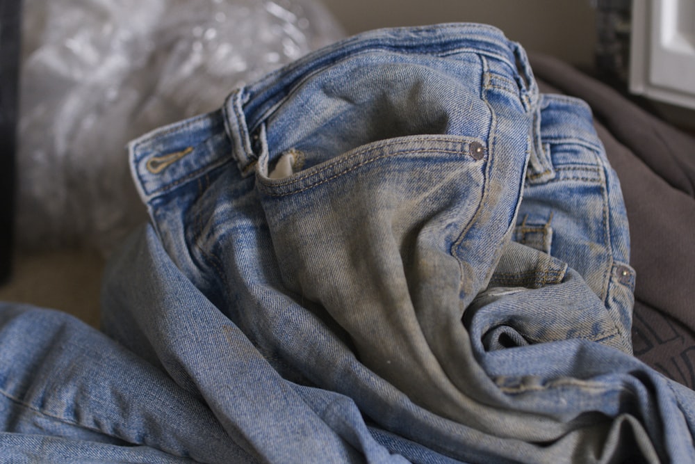 a pile of jeans sitting on top of a bed