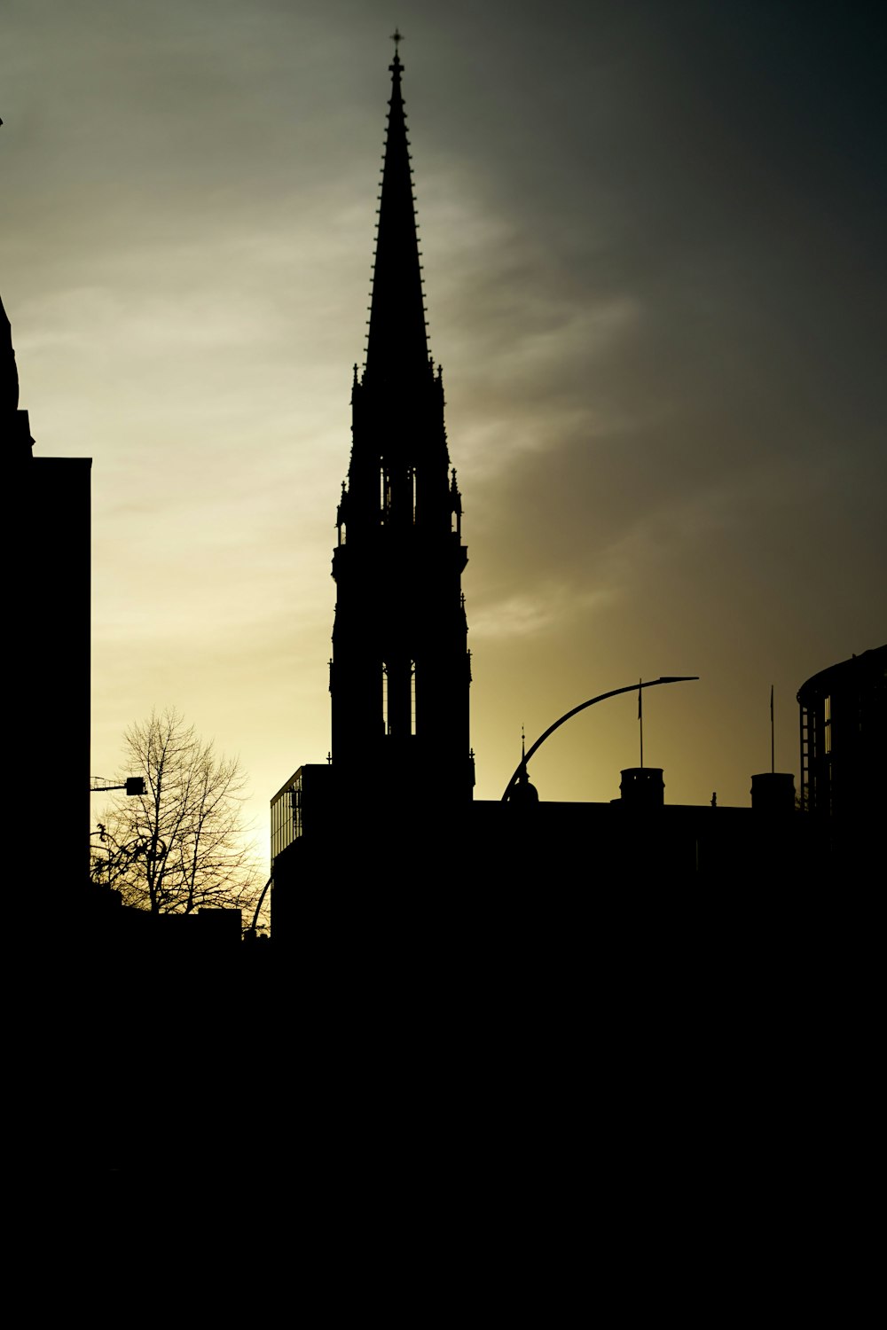 the silhouette of a church steeple against a cloudy sky