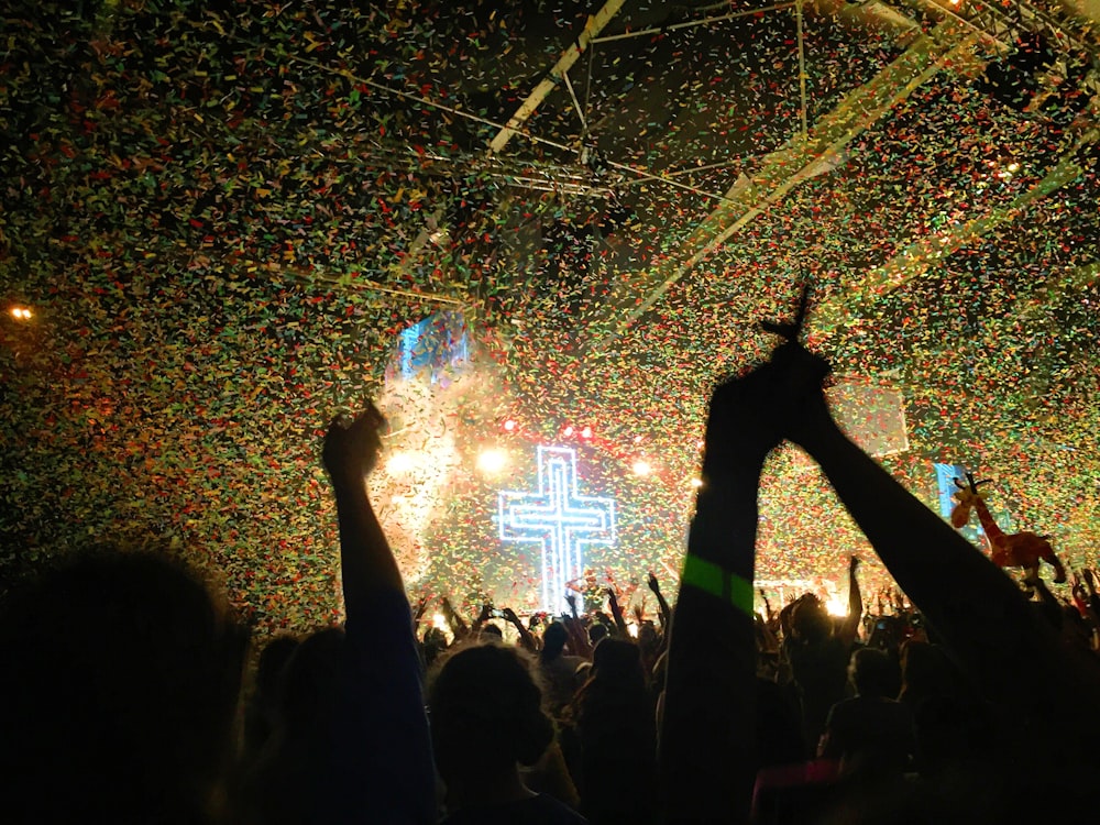 a crowd of people at a concert with confetti on the ceiling