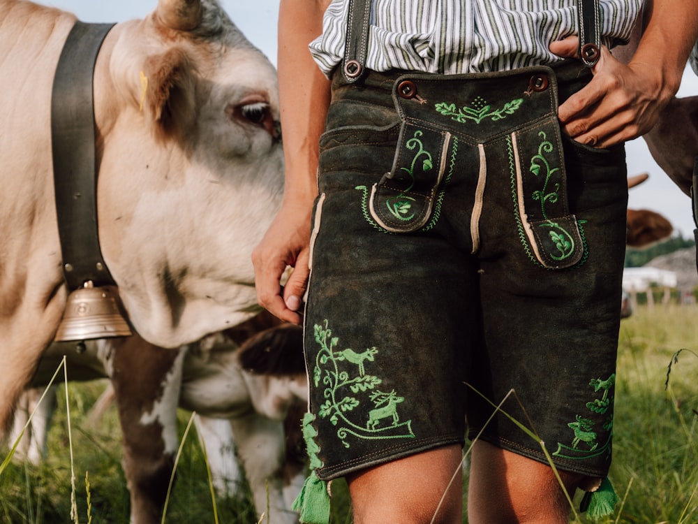 a man standing next to a cow in a field