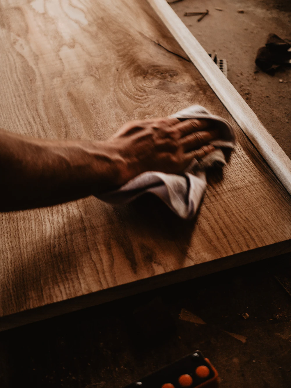 Person wiping a piece of wood during finishing