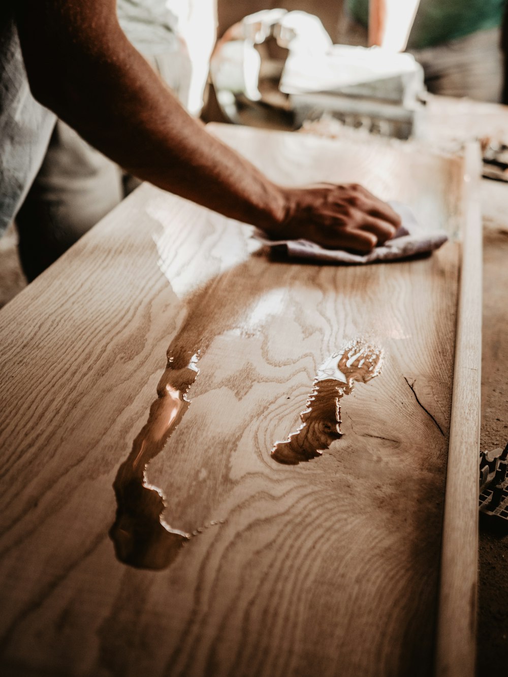 una persona che pulisce un tavolo di legno con un panno